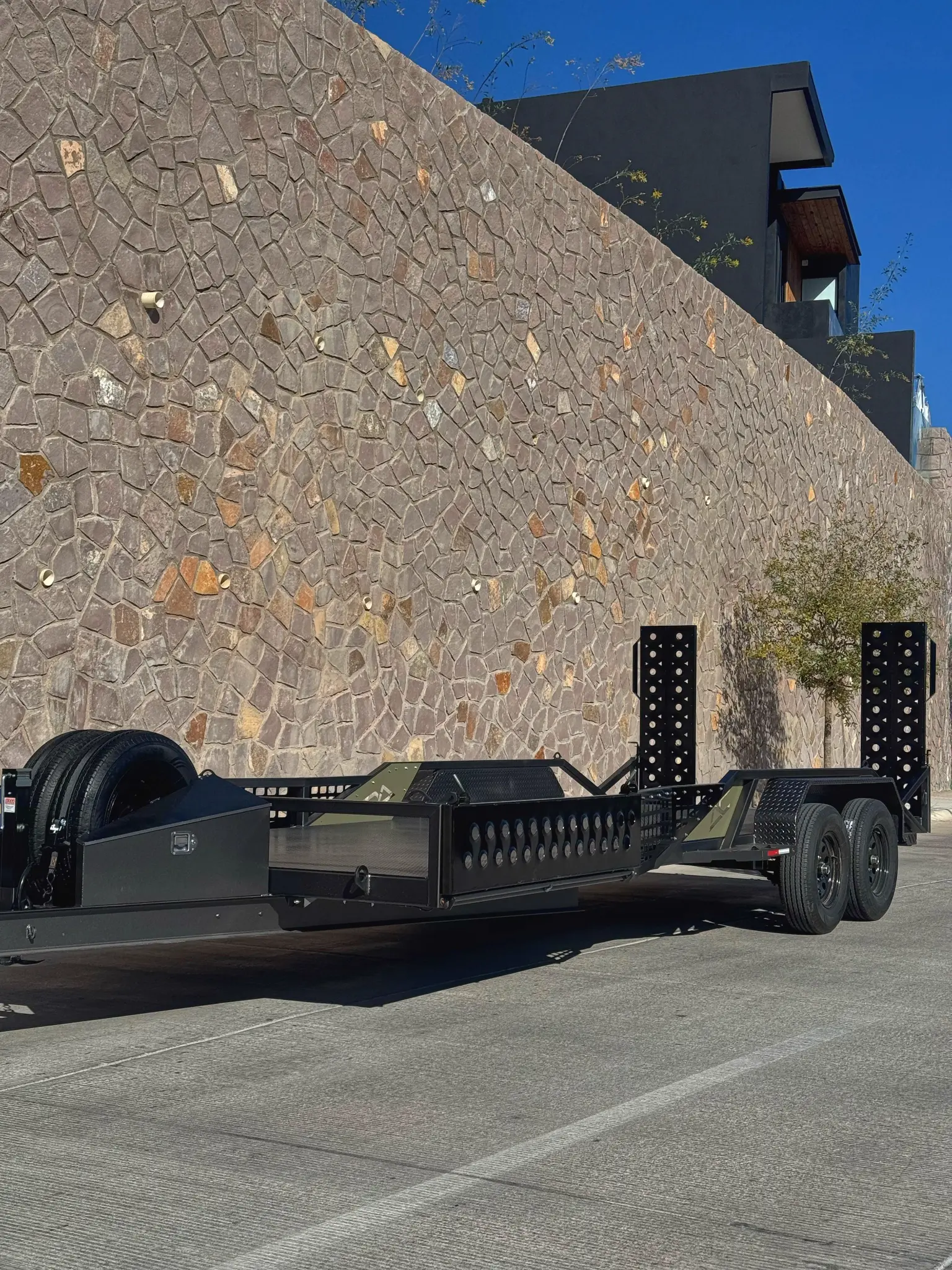 Matte black custom equipment trailer with perforated loading ramps and heavy-duty construction - AC Solutions Industries